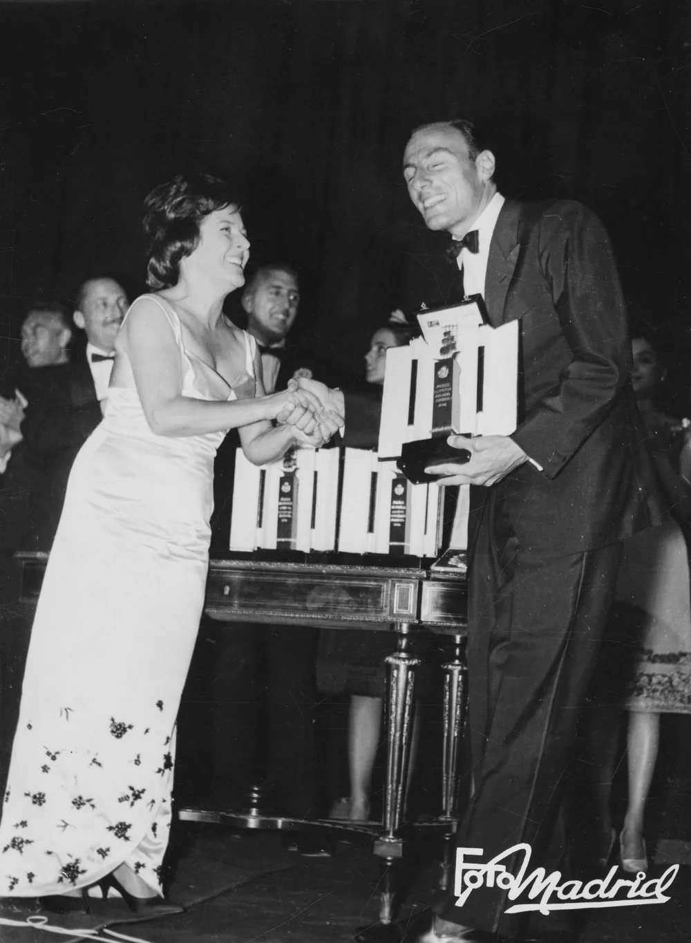 Imperio Argentina estrecha la mano de Alberto Fioretti junto a una mesa de premios, en el Teatro Victoria Eugenia de San Sebastián en 1962.